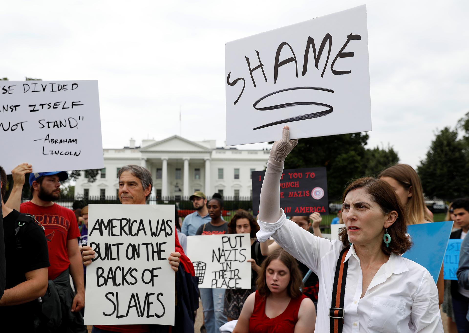 Protesters hold signs in front of the White House