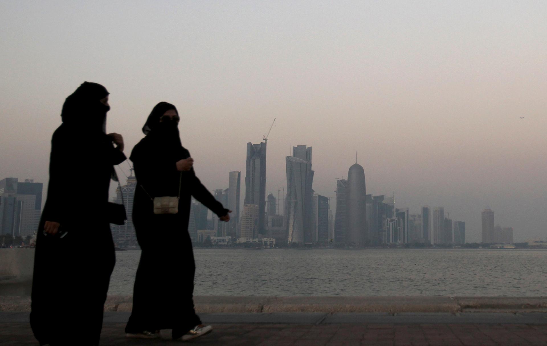 Women walk past buildings as the sun sets in Doha October 19, 2010.