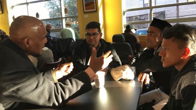 (From right) Muhammad Anwar and Hussein Muhammad (wearing a hat) chat with Ibrahim Rashid, an intern with IINE (center), and a community member.