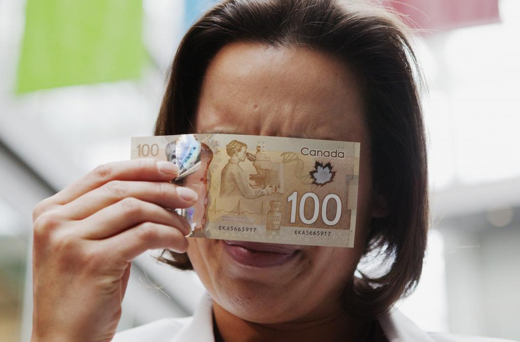 Martine Warren, a scientific advisor to the Bank of Canada, demonstrates how to view a security feature on the new polymer Canadian 100 dollar bill to reveal hidden numbers when pointed at a single point light source in Toronto November 14, 2011.