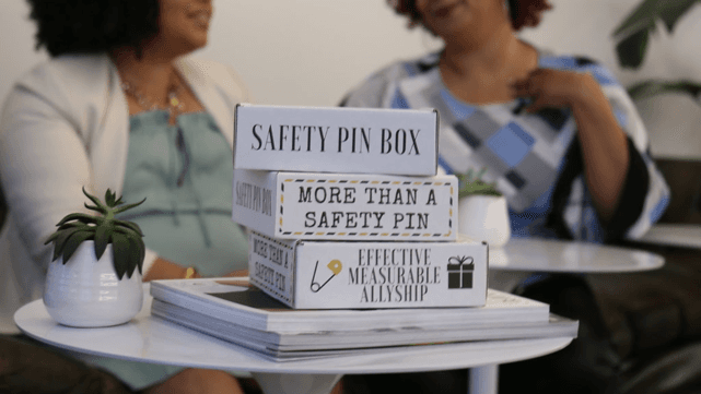 Boxes on tables with labels: "Safety pin box," "More than a safety pin," "Effective measurable allyship"