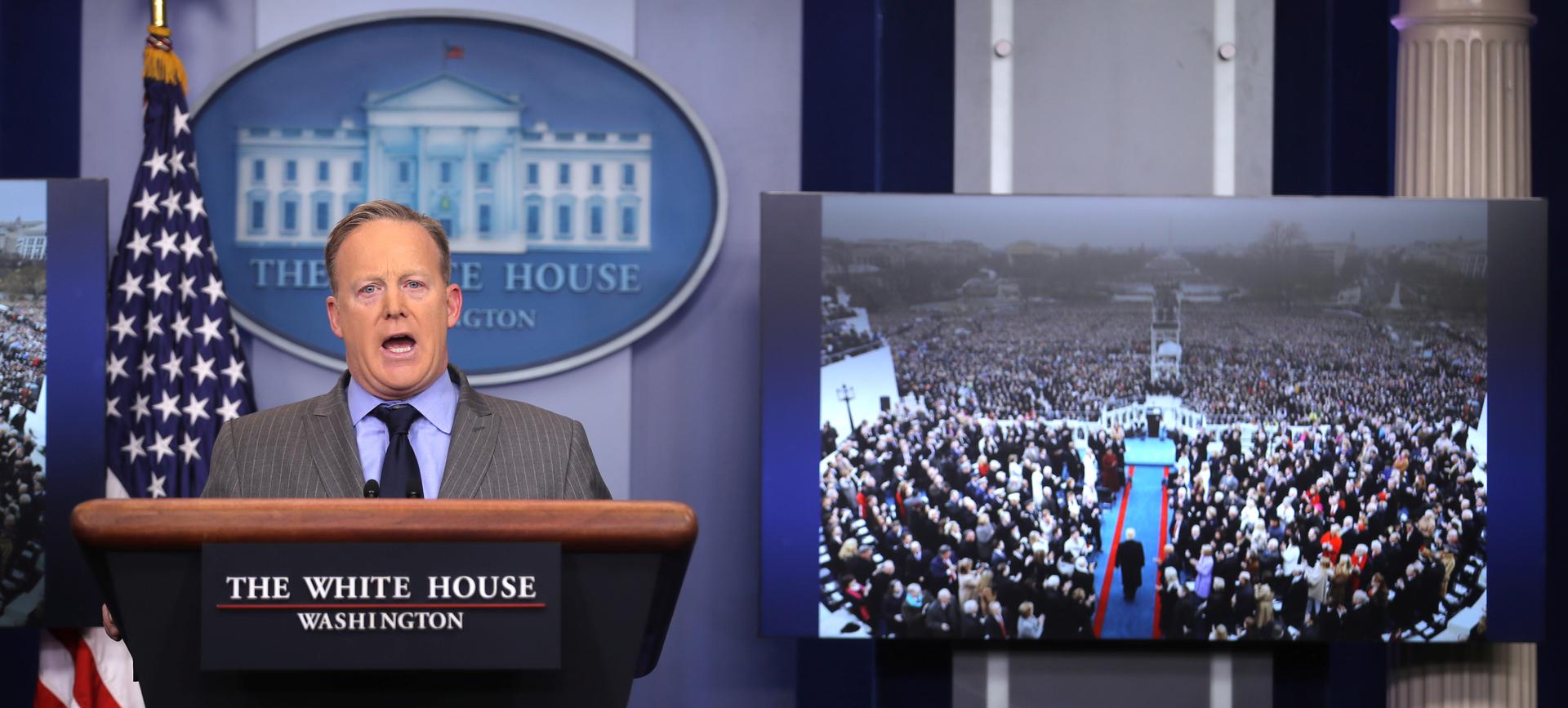 Press Secretary Sean Spicer delivers a statement while television screen show a picture of U.S. President Donald Trump's inauguration