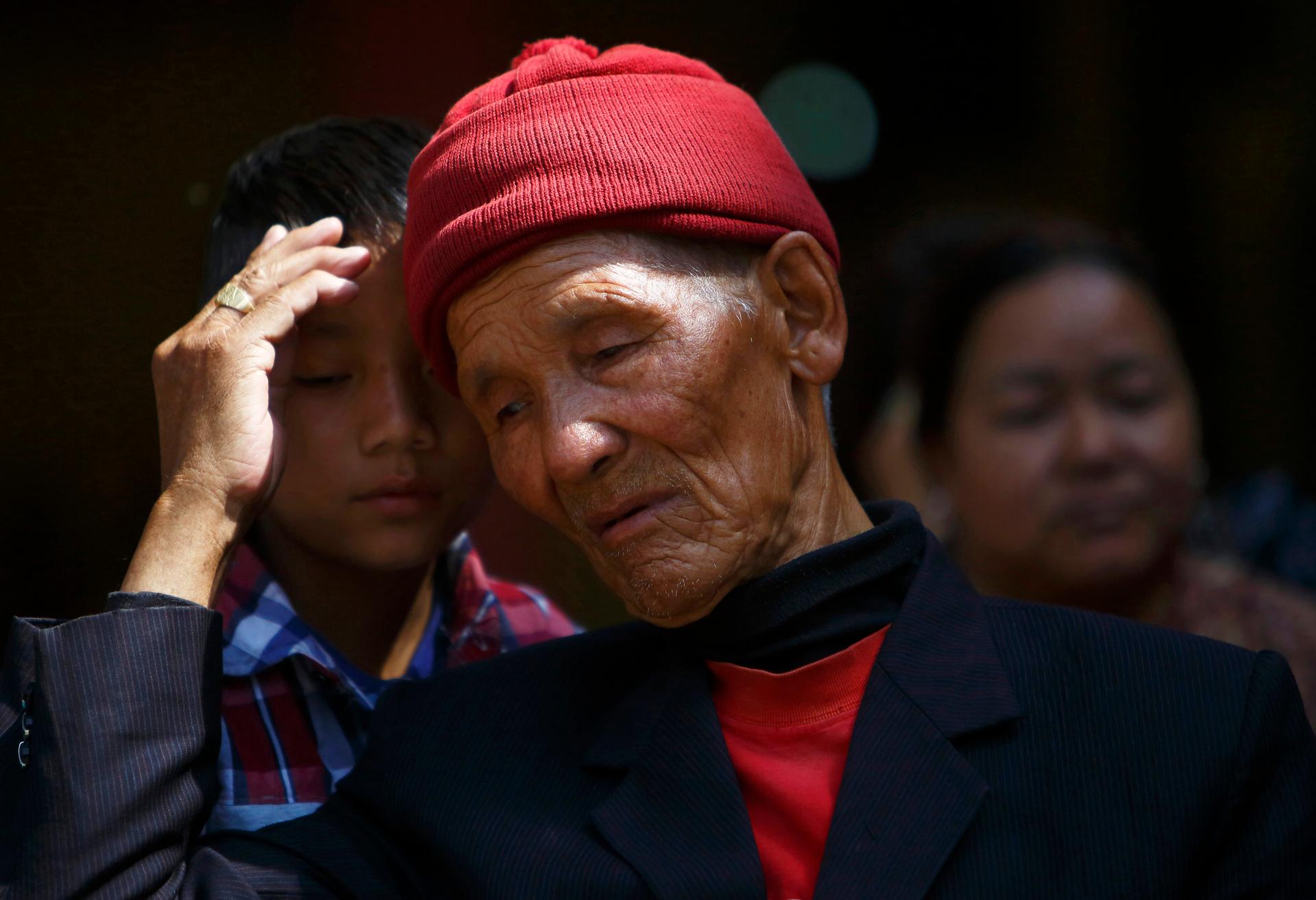 The father of Kaji Sherpa, one of 13 Nepali mountaineering guides who lost his life in an avalanche on Mount Everest, comforts his grandson as he waits for the body of his son to arrive at Sherpa Monastery in Kathmandu April 19, 2014.