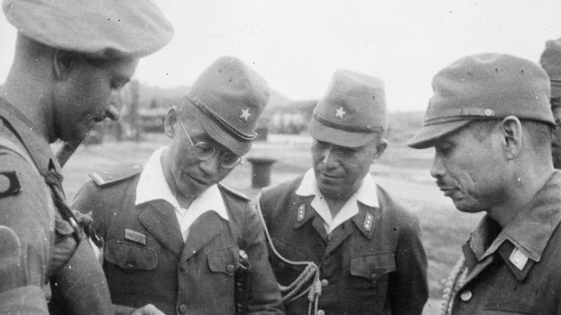Japanese Army officers confer with a British Army officer after the Japanese surrender of Singapore, 1945.