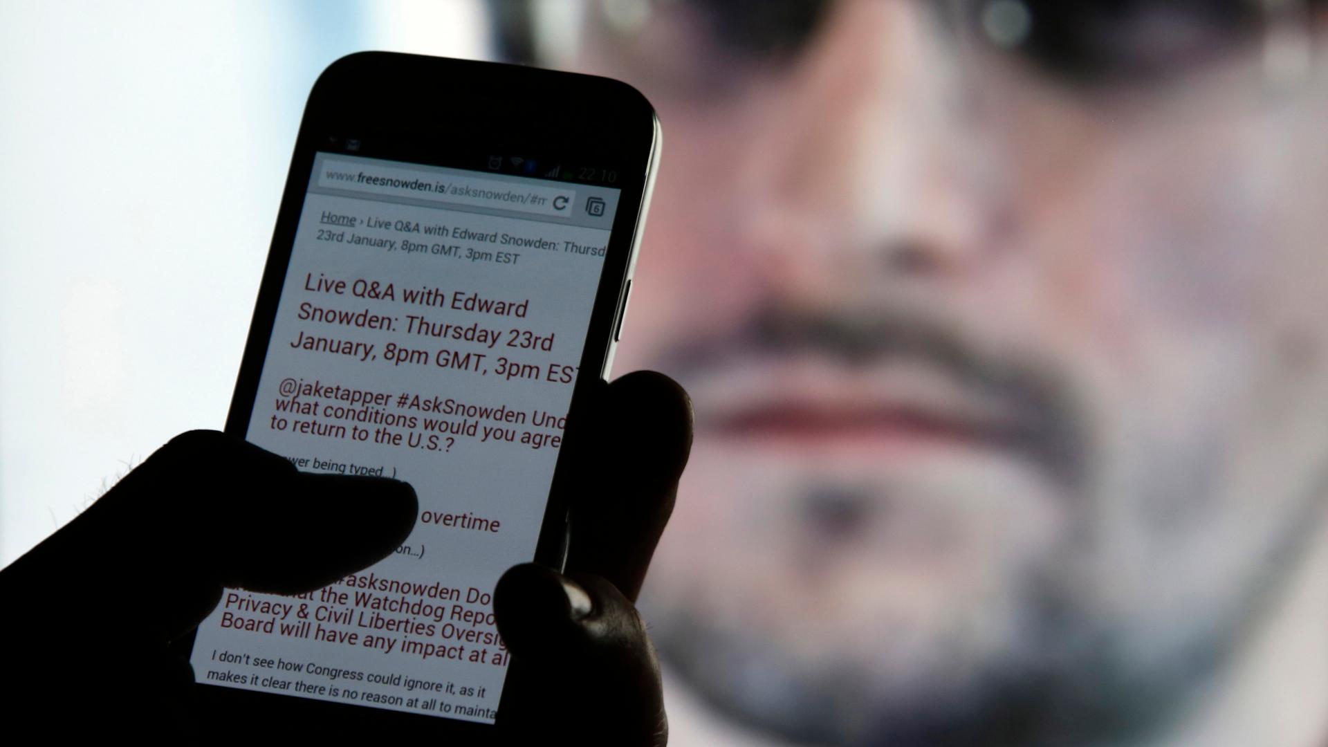 A man uses his phone to read updates about former American NSA contractor Edward Snowden answering users' questions on Twitter.