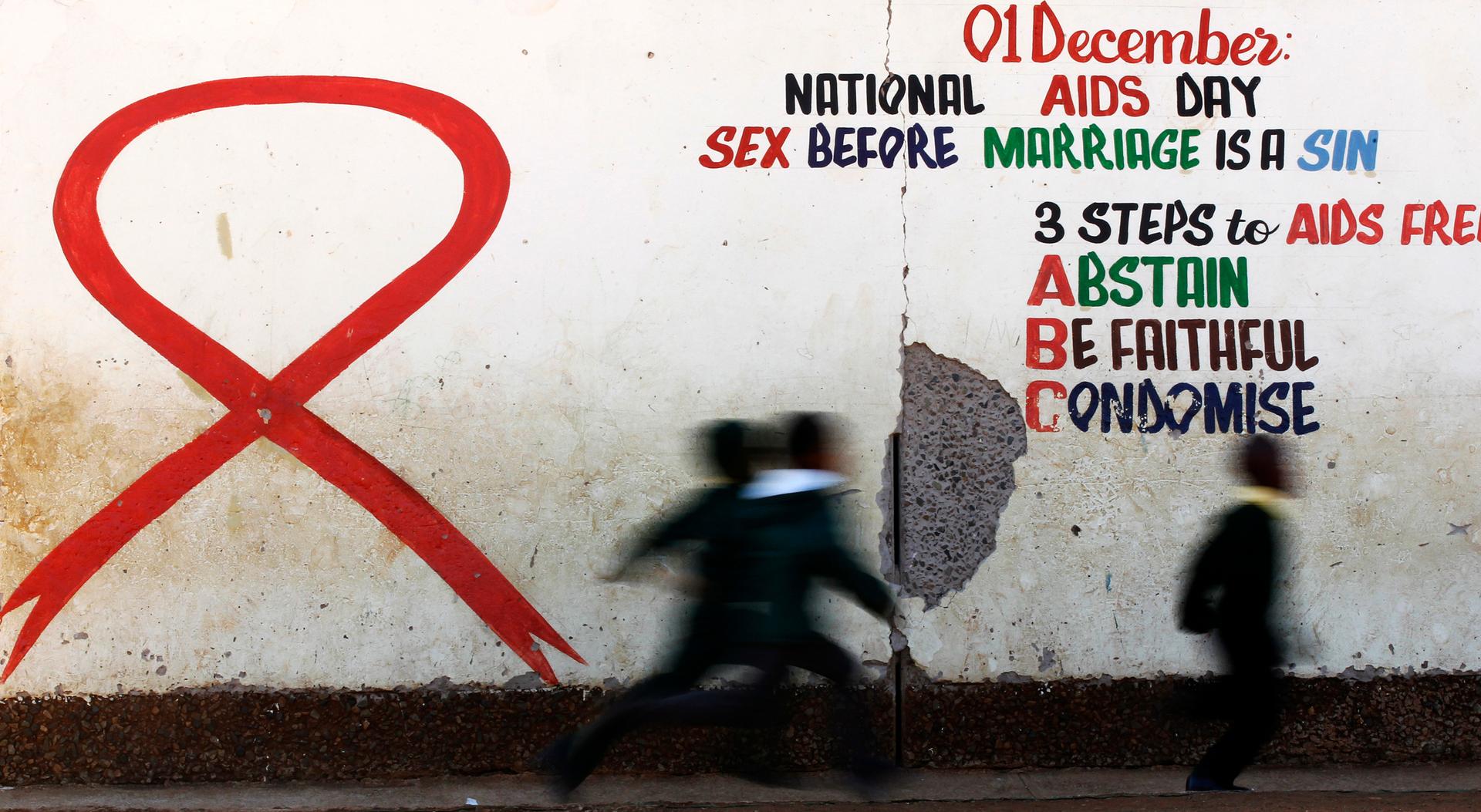 Children run past a mural painting of an Aids ribbon at a school in Khutsong Township, 74 km (46 miles) west of Johannesburg, August 22, 2011.
