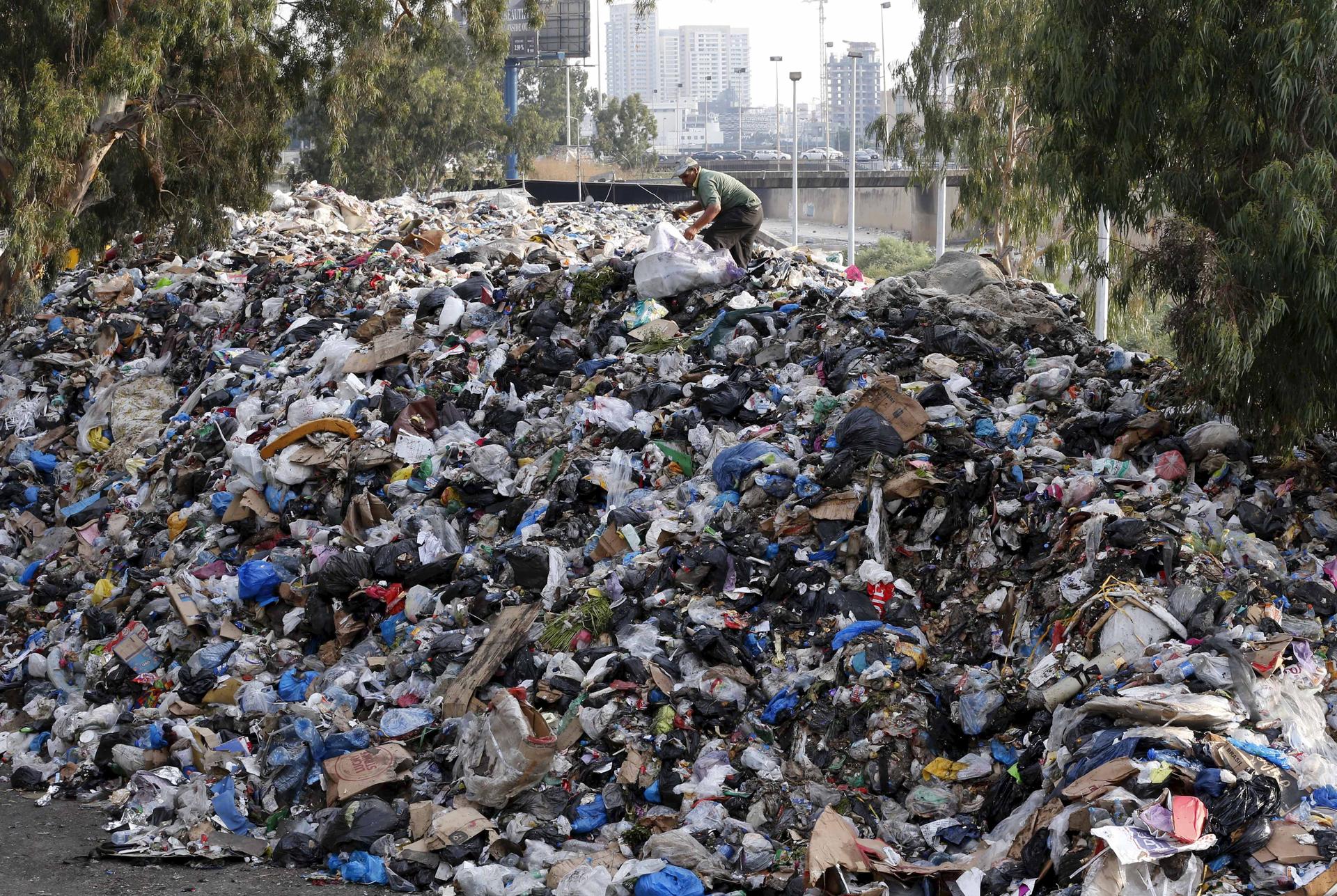 A scavenger sifts through garbage piled on the banks of a Beirut river.  