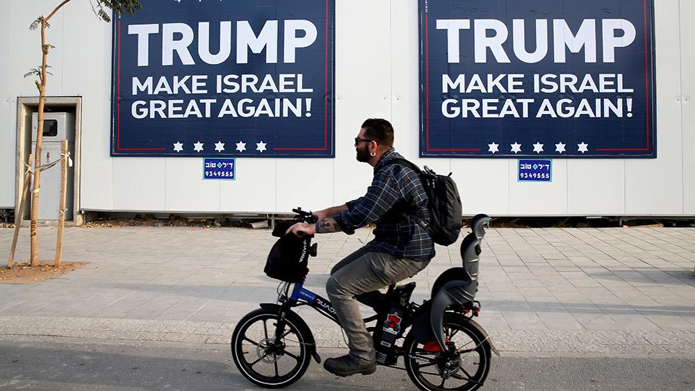 A man cycles past signs bearing the name of U.S. President-elect Republican Donald Trump in Tel Aviv, Israel.