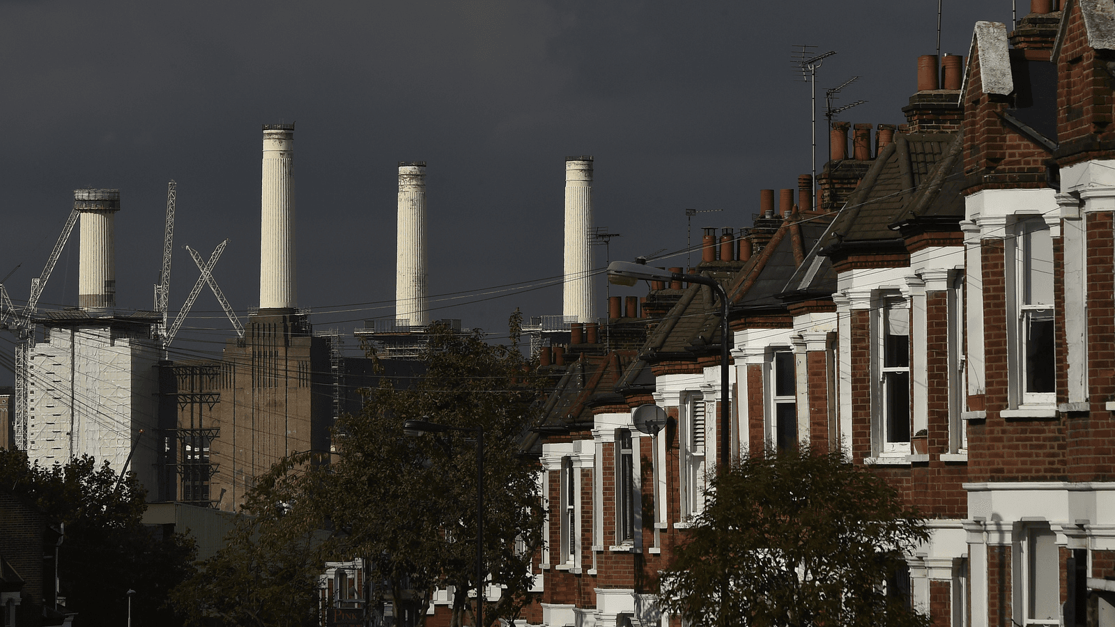 A rig (L) surrounds the top of one of the chimneys of Battersea Power Station as demolition work is carried out, in London, Oct. 2, 2014. 