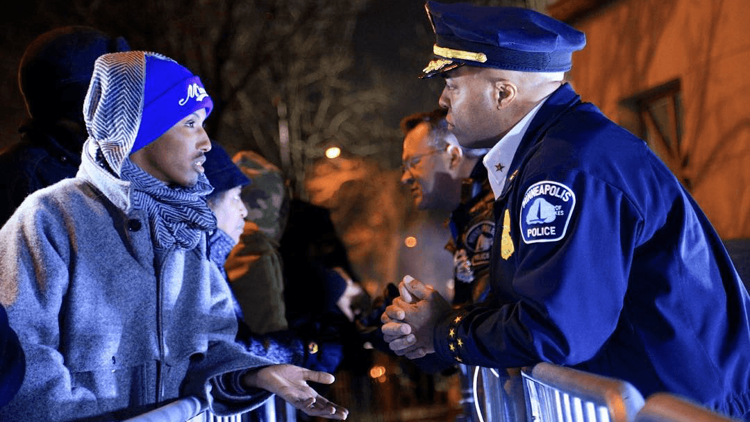 Mohamed Samatar talks to a Minneapolis police officer over a barrier.