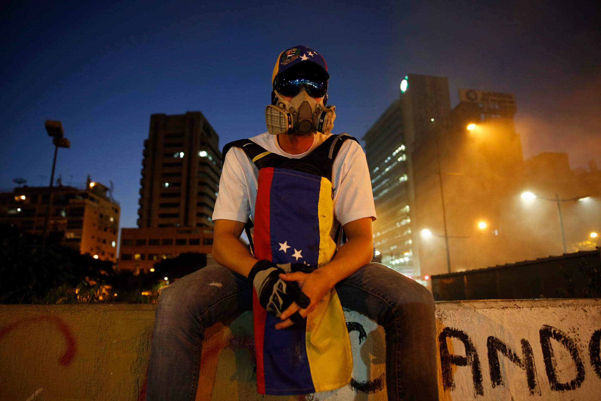 An opposition supporter sits on a wall as protesters block a street at Altamira square in Caracas February 20, 2014.
