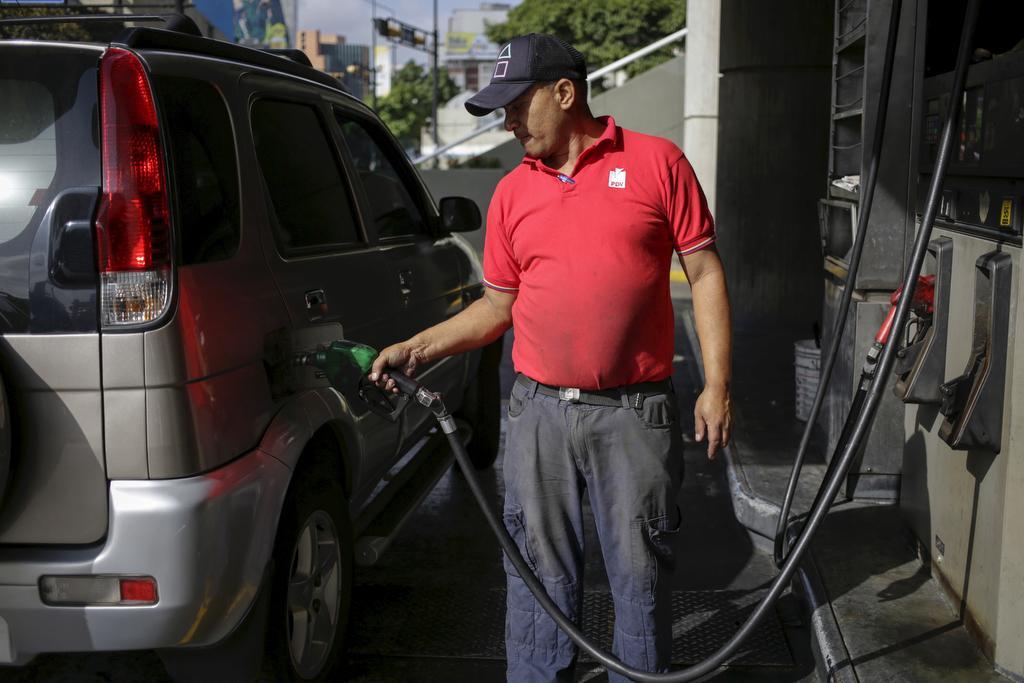 A worker pumps gas into a vehicle at a gas station, which belongs to Venezuela's state oil company PDVSA, in Caracas, on Feb. 12, 2016. 