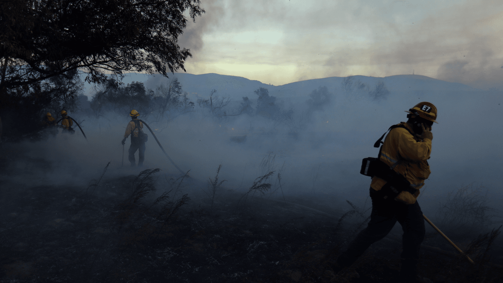 Firefighters work to put out hot spots on a fast moving wind driven wildfire in Orange, California, Oct. 9, 2017.