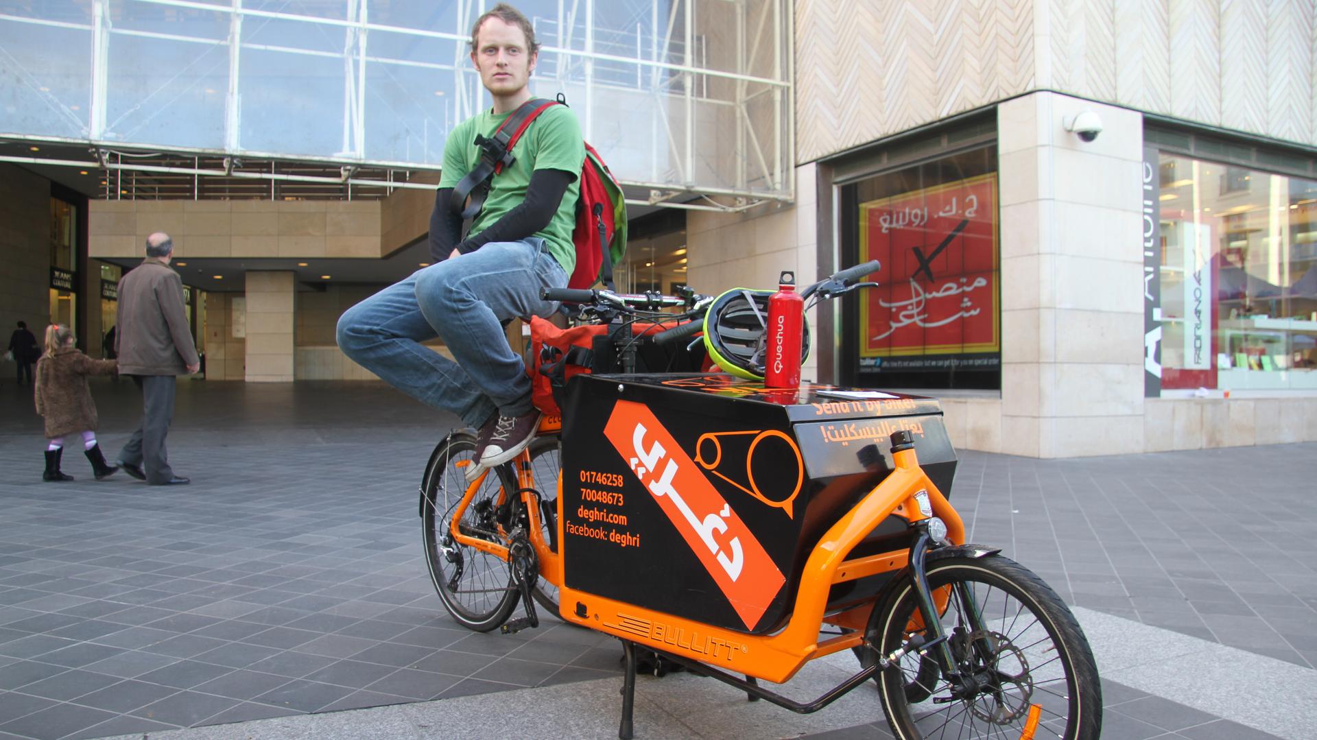 Degheri coFounder Matt Saunders sits with the team's "Cargo Bike" outside a shopping district in downtown Beirut, Degheri messengers are trying to attract clients by offering to bike their groceries home for them. 