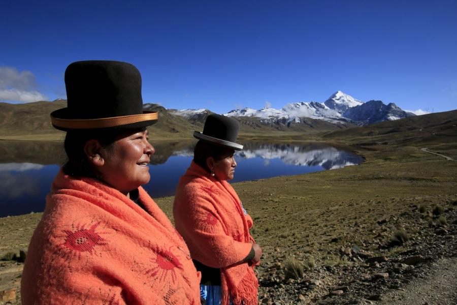 Aymara indigenous women Lidia Huayllas, 48, (L) and Dora Magueno, 50, stand near Milluni lake, with the Huayna Potosi mountain in the background, Bolivia.