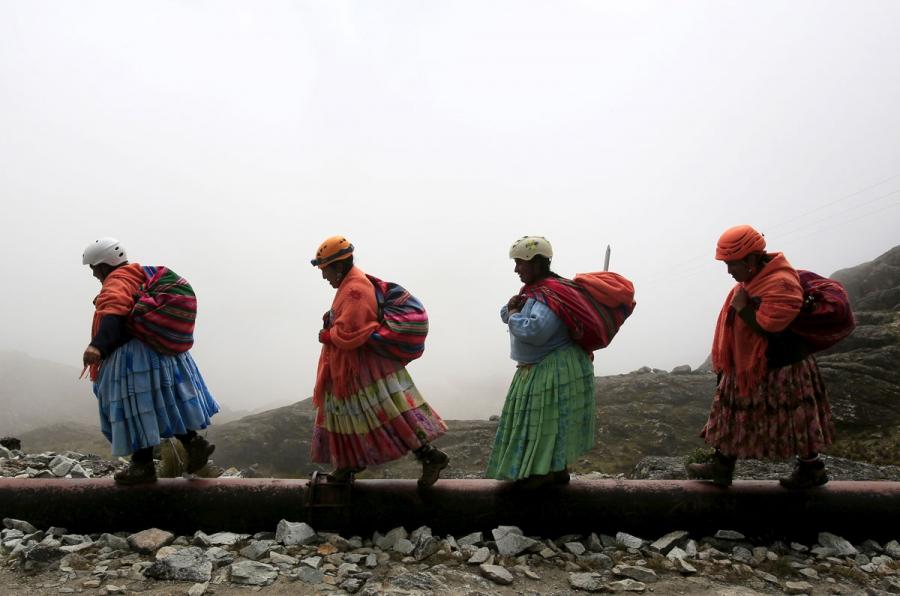 Aymara indigenous women walk toward Huayna Potosi mountain.