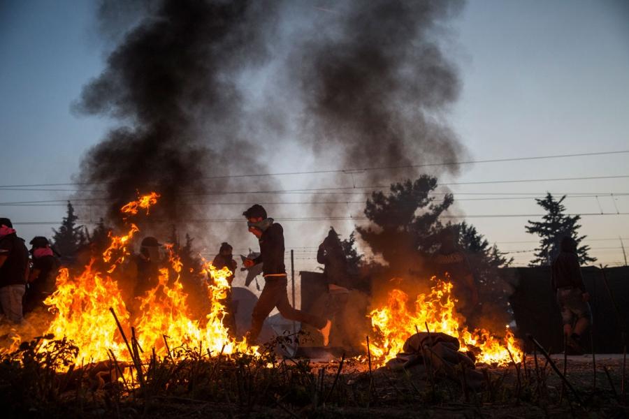 A protester walks past a fire lit during clashes at the camp.