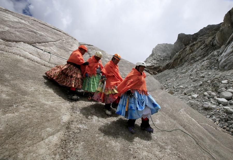 Aymara indigenous women practice descending on a glacier at the Huayna Potosi mountain.