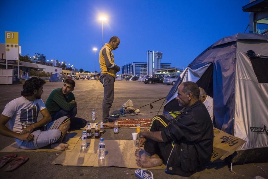 Alhasan Abdulghan from Aleppo, Syria, prays after iftar next to the collection of tents where he and hundreds of other refugees and migrants are living at Piraeus Port Terminal 1 in Athens, Greece. His friends, clockwise from left, Mazan, from Homs, Fahri