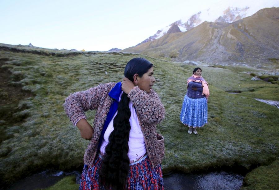 Aymara indigenous women fix their hair at their camp at Illimani mountain.