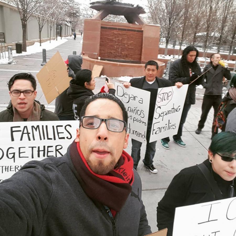 Diaz takes a selfie in front of protesters holding signs