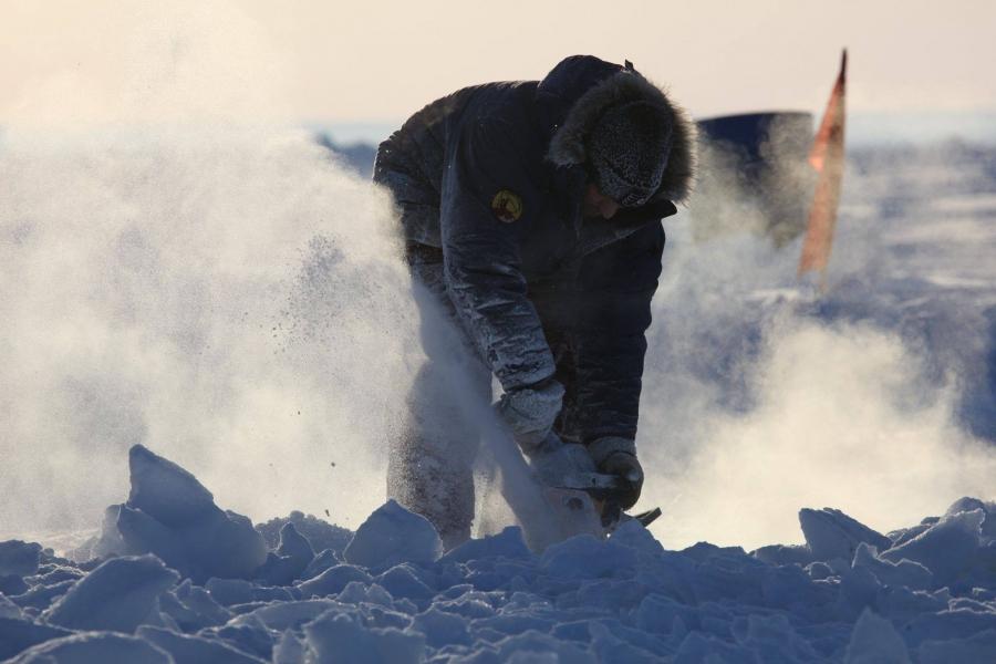 A worker carves into the ice at Barneo Ice Camp.