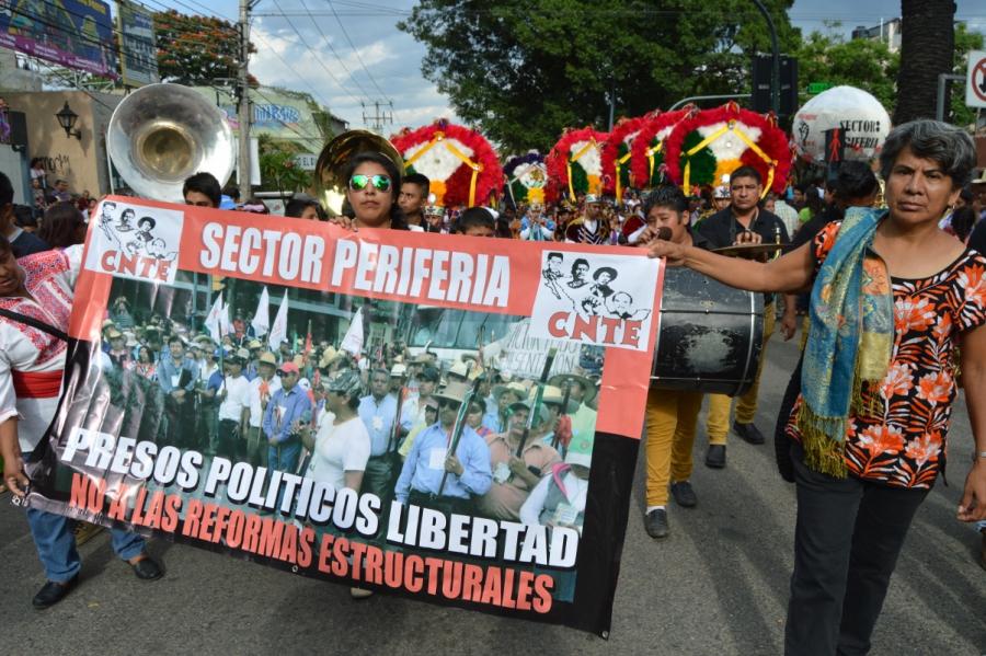 Teachers from the Oaxaca City outskirts march with a delegation of dancers and musicians with a banner calling for the release of political prisoners