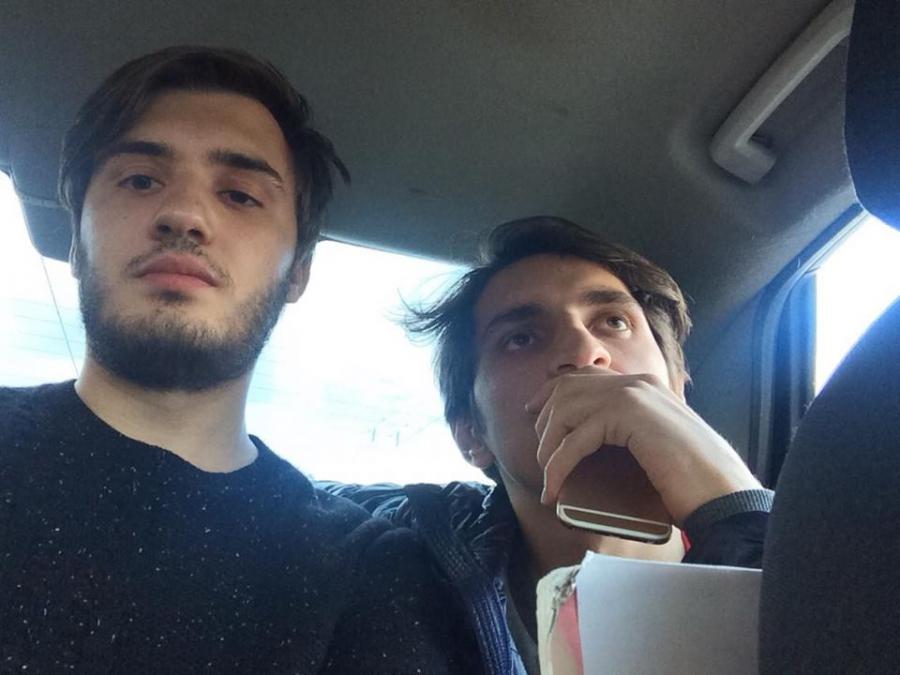 Felix Glyukman and Islam Abdullabeckov being escorted in police vehicle after being detained by Russian authorities. 