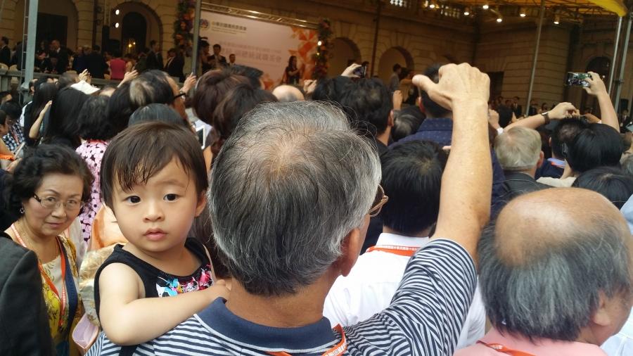 Young girl carried by man faces camera while man cheers in crowd
