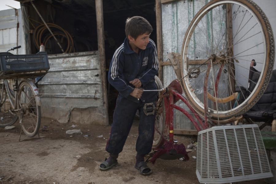 Ebraham Alatmia, 11, a Syrian refugee from Daraa, fixed a bicycle in a makeshift bike shop where he works in the main marketplace nicknamed Champs-Elysée.