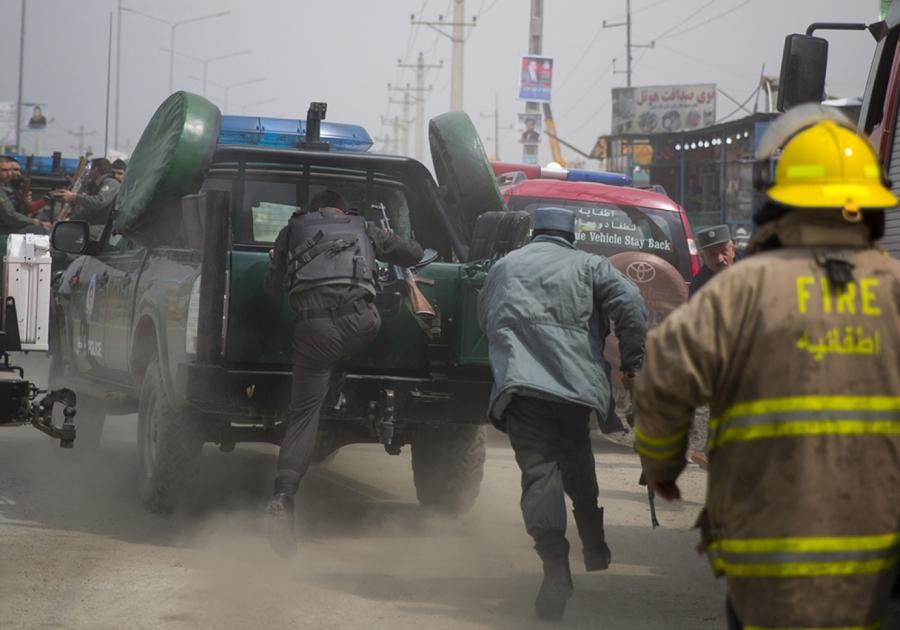 Afghan policemen run to jump on their car as Taliban militants attacked the main Afghan election commission's headquarters on the outskirts of Kabul, Afghanistan, firing on the compound with rocket-propelled grenades and heavy machine guns from a house ou