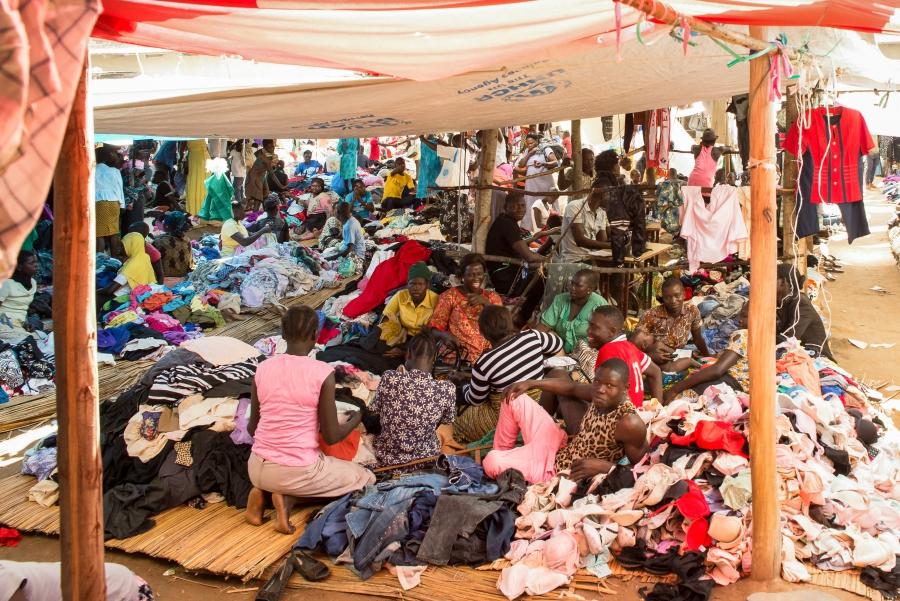 Vendors at a market in Arua, Uganda, relax under plastic tarp emblazoned with the United Nations High Commissioner for Refugees logo.