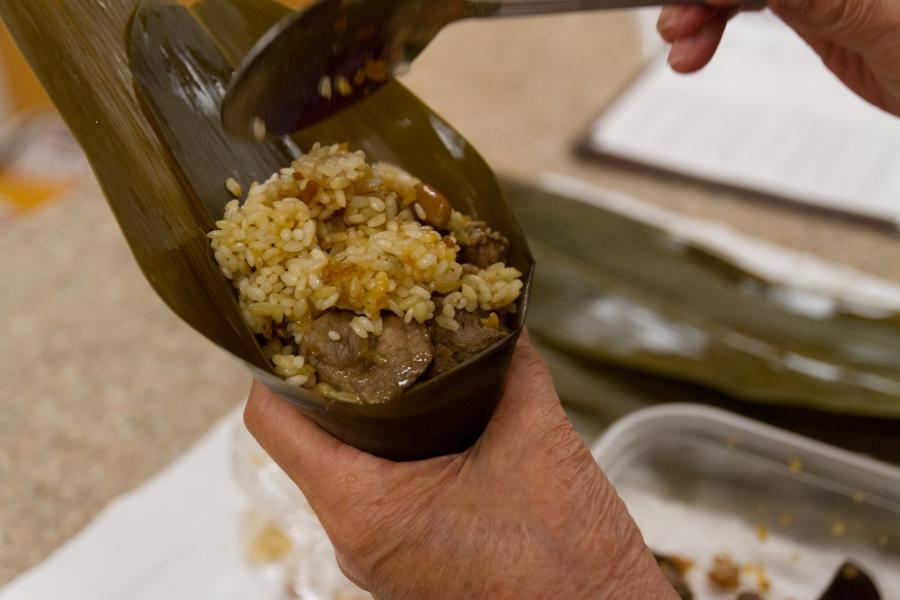 Spoon fills bamboo leave packet with rice