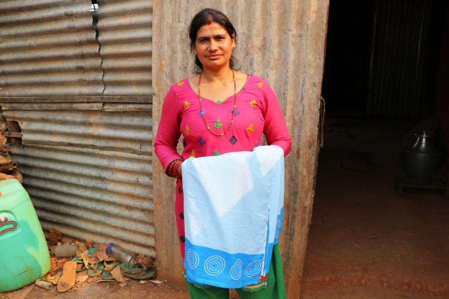Bimala Parajuli holds up the bright blue sari that she pulled from the rubble of her destroyed house. She wears this uniform when making house calls to check on women and children in her village.