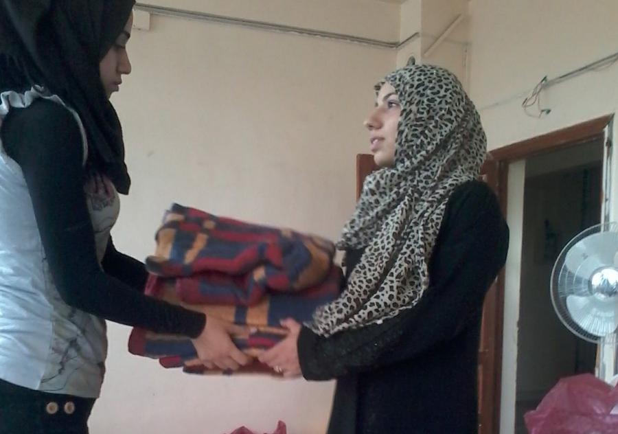A Questscope volunteer gives a blanket to a woman who fled her home near the Syrian city of Hama after fighting there earlier this year. 