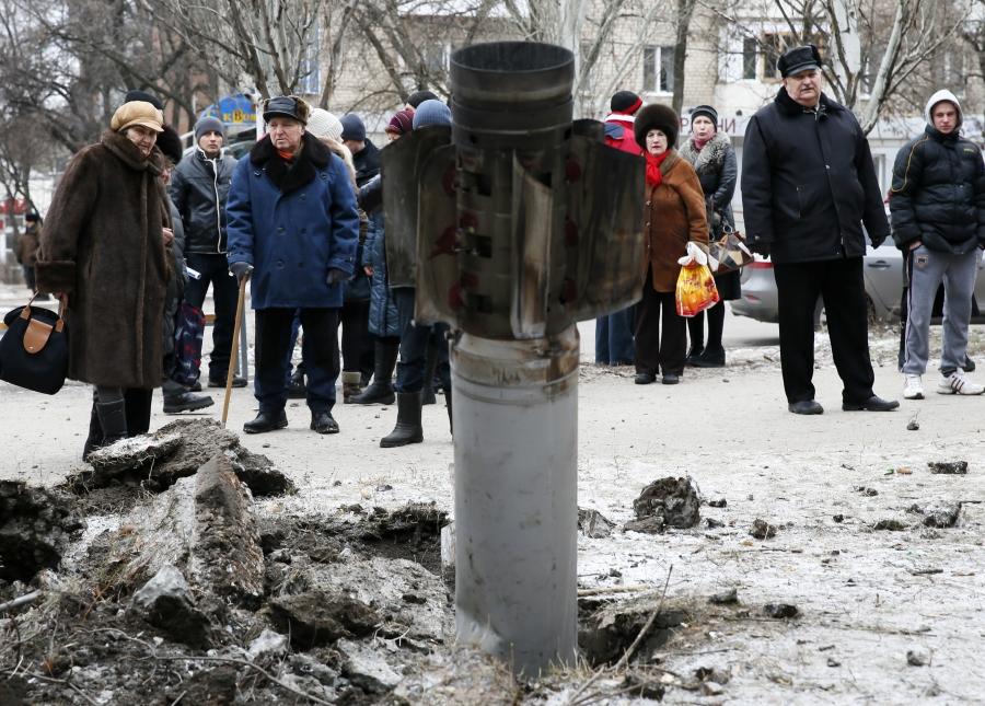 People look at the remains of a rocket shell on a street in the town of Kramatorsk, eastern Ukraine February 10, 2015.