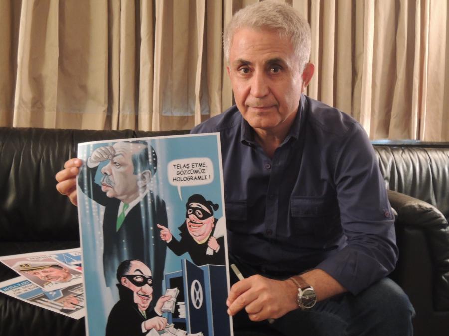 Photo of Turkish cartoonist Musa Kart holding a cartoon that prompted a law suit from President Erdogan who charged the cartoonist with insult and slander. The cartoon depicted the Turkish president as a hologram keeping a watchful eye over a robbery. Kar