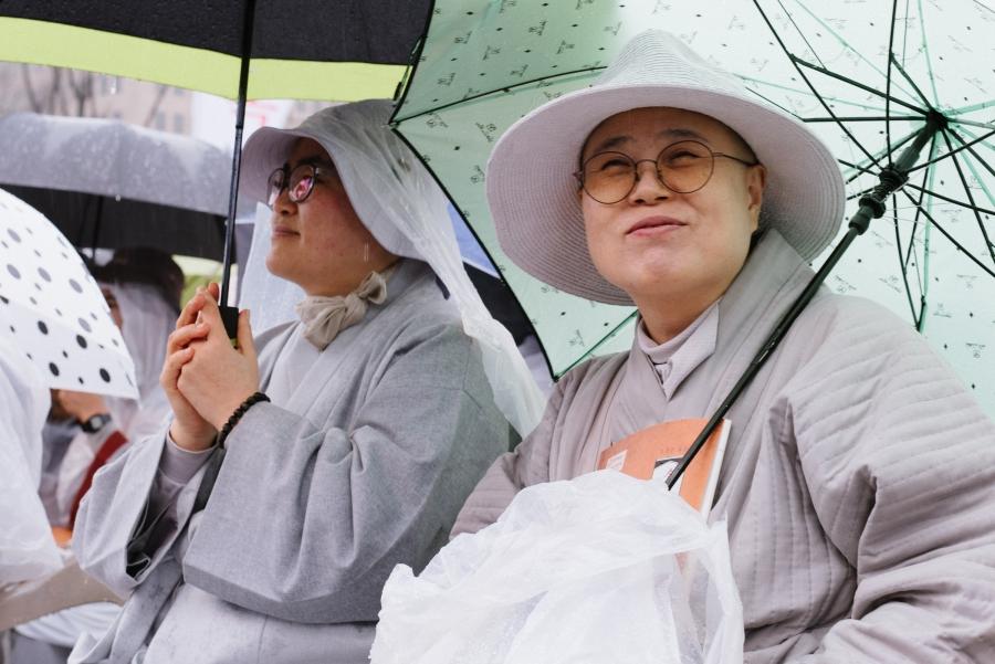 Buddhist nuns, along with monks and laypeople, tried to stay dry at this year's annual public reading of the Diamond Sutra in downtown Seoul.  