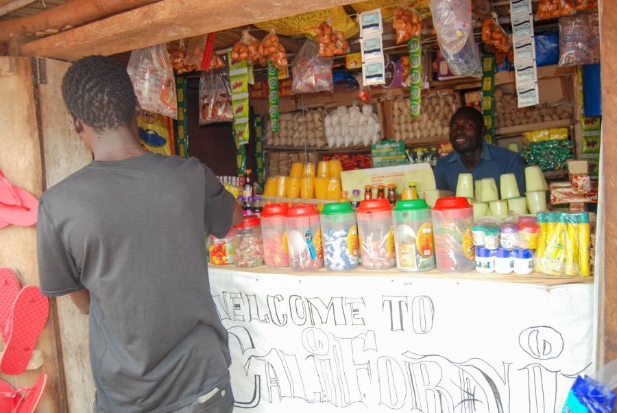 Nelson Doko sits behind the counter of his small shop in Uganda's Bidi Bidi refugee settlement. Business is slow, he says, since nobody has any money.