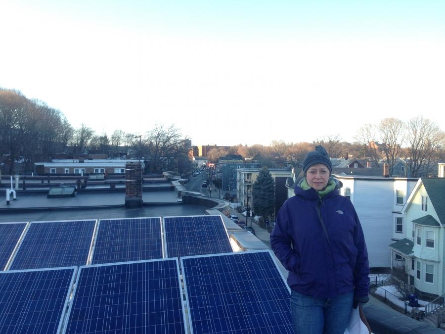 Edith Buhs, with the solar panels she recently installed on the roof of her Boston building. The electricity from the system supplies about half of the needs of the building's three apartments, but most of it flows first onto the electric grid. It's a sys