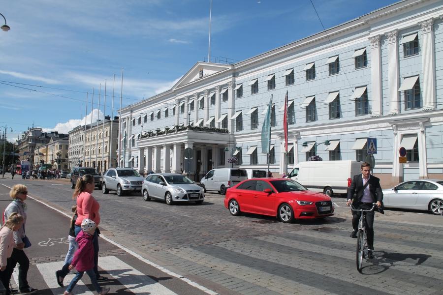 Cyclists, pedestrians and cars coexist outside Helsinki City Hall.