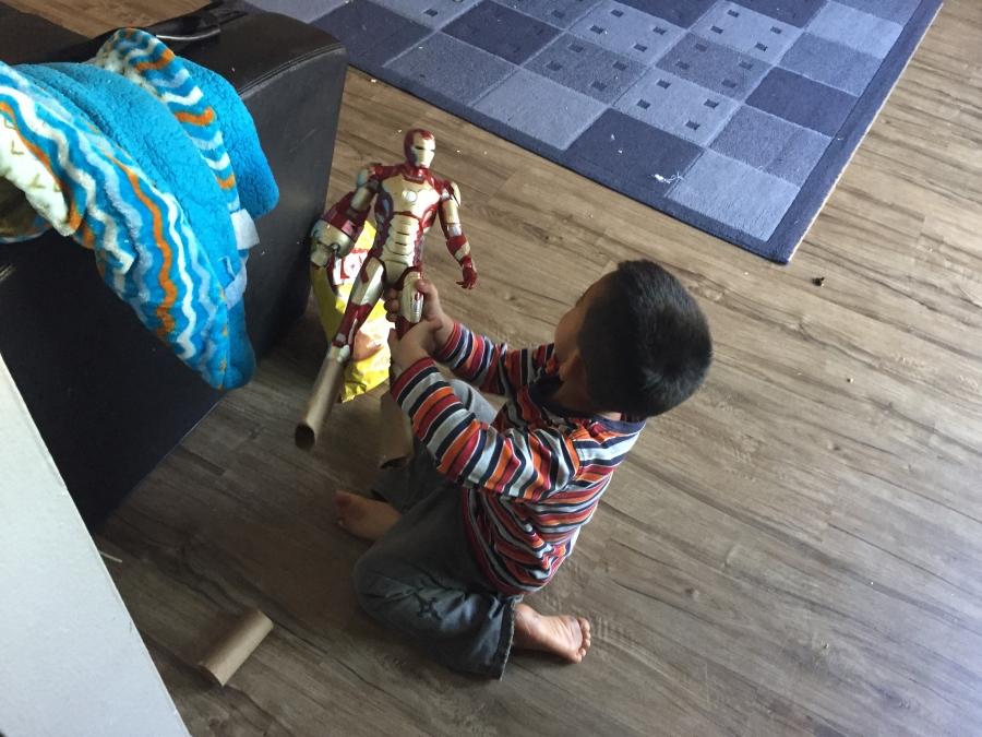 Boy sitting on floor playing with action figure