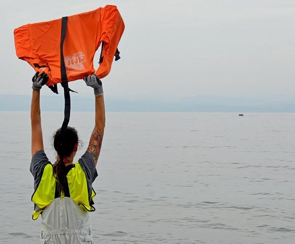 A volunteer signals to a refugee boat near Skala Syknaminia.