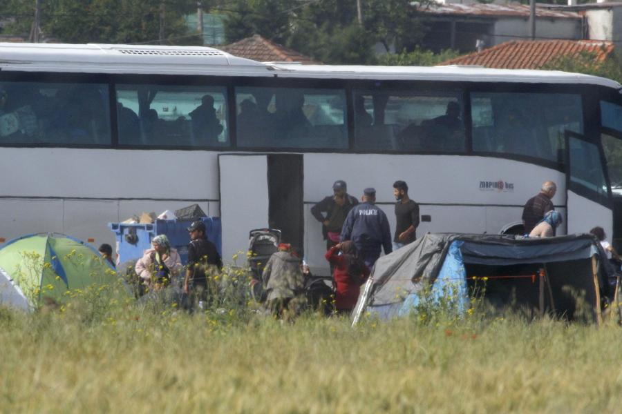 Police watch as refugees and migrants board buses to be tranferred to government camps, during an operation to evacuate a makeshift camp at the Greek-Macedonian border near the village of Idomeni, Greece, May 24, 2016.