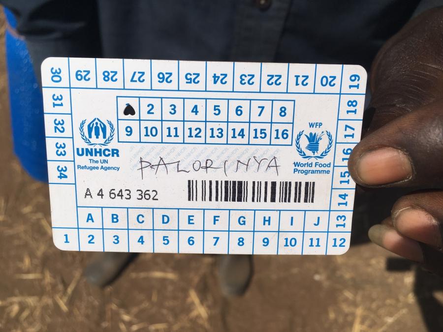 Asobasi Francis Wani hold up the UNHCR punch card he was given when he was registered, indicating that he is here alone. He was separated from his two wives and four children when his village in Kajo-Keji county was attacked. He hopes to locate his family