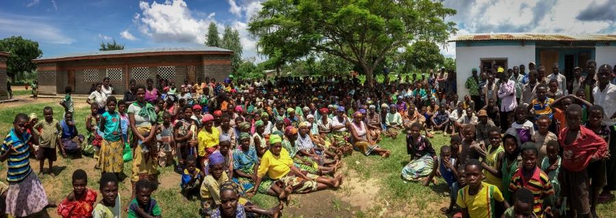 Some of the 2,000 flood victims now sheltered at the Milala Primary School in Makawa gather on the gather outside two of the school's buildings. Malaria and malnutrition are starting to take hold in the isolated camp.