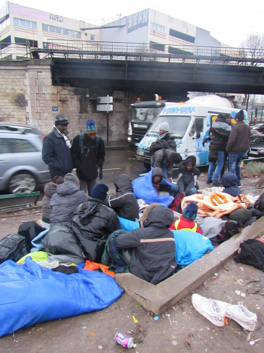A group of Sudanese migrants huddles on top a subway grate in northern Paris to keep warm.