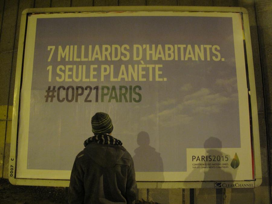 Joel Domenjoud stands in front of a billboard near his Paris home heralding the climate conference. It says: “7 billion inhabitants. 1 single planet.” Domenjoud is one of at least 24 climate activists placed under curfew for the duration of the conference