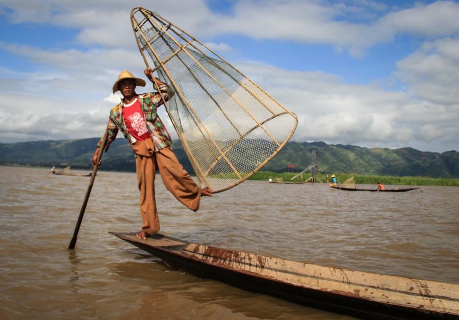 One of Inle Lake's traditional fishermen perches on the prow of his canoe. 