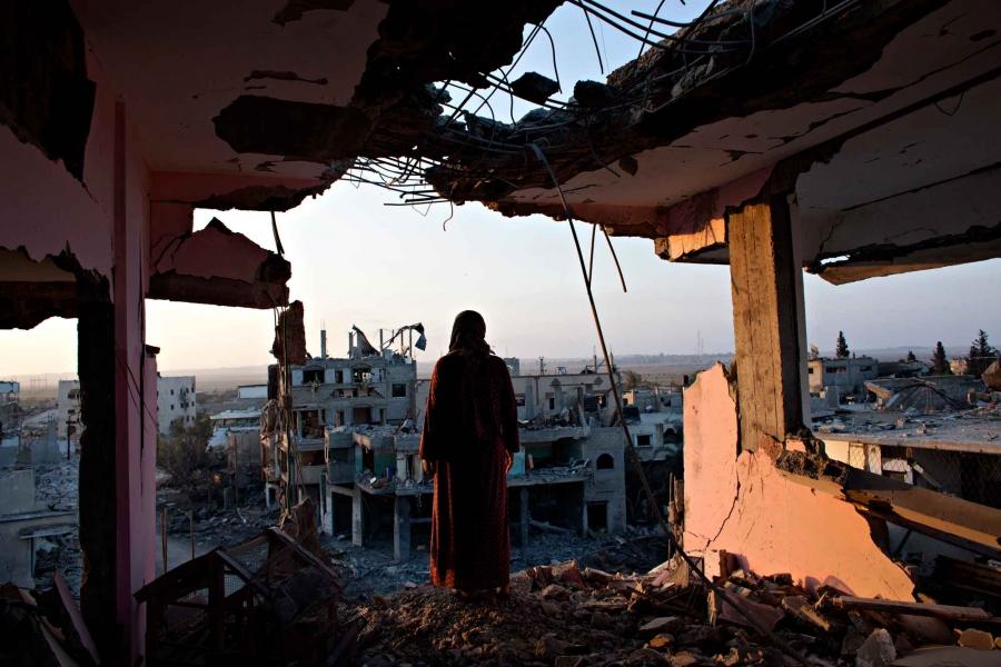 Hidya Atash stands on the top floor of her home as she overlooks the destruction in Shujayea at dawn Aug. 8, 2014. Her family's home was hit two weeks ago by a warning rocket and the family of 40 people fled. When they returned during the recent cease-fir